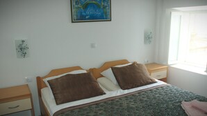 Un dormitorio con cama, dos almohadas, una mesita de noche y un cuadro en la pared.
