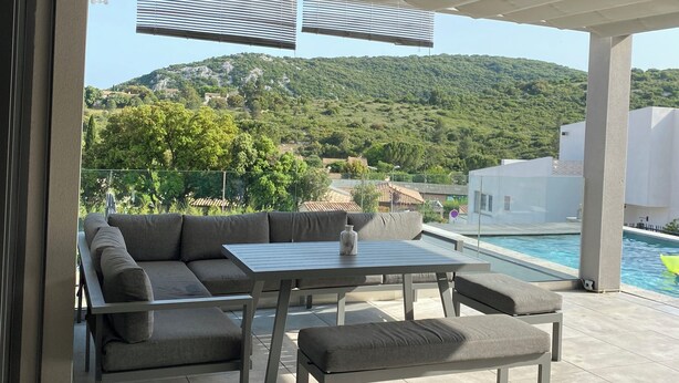 An outdoor patio with a sofa, table, and pool.