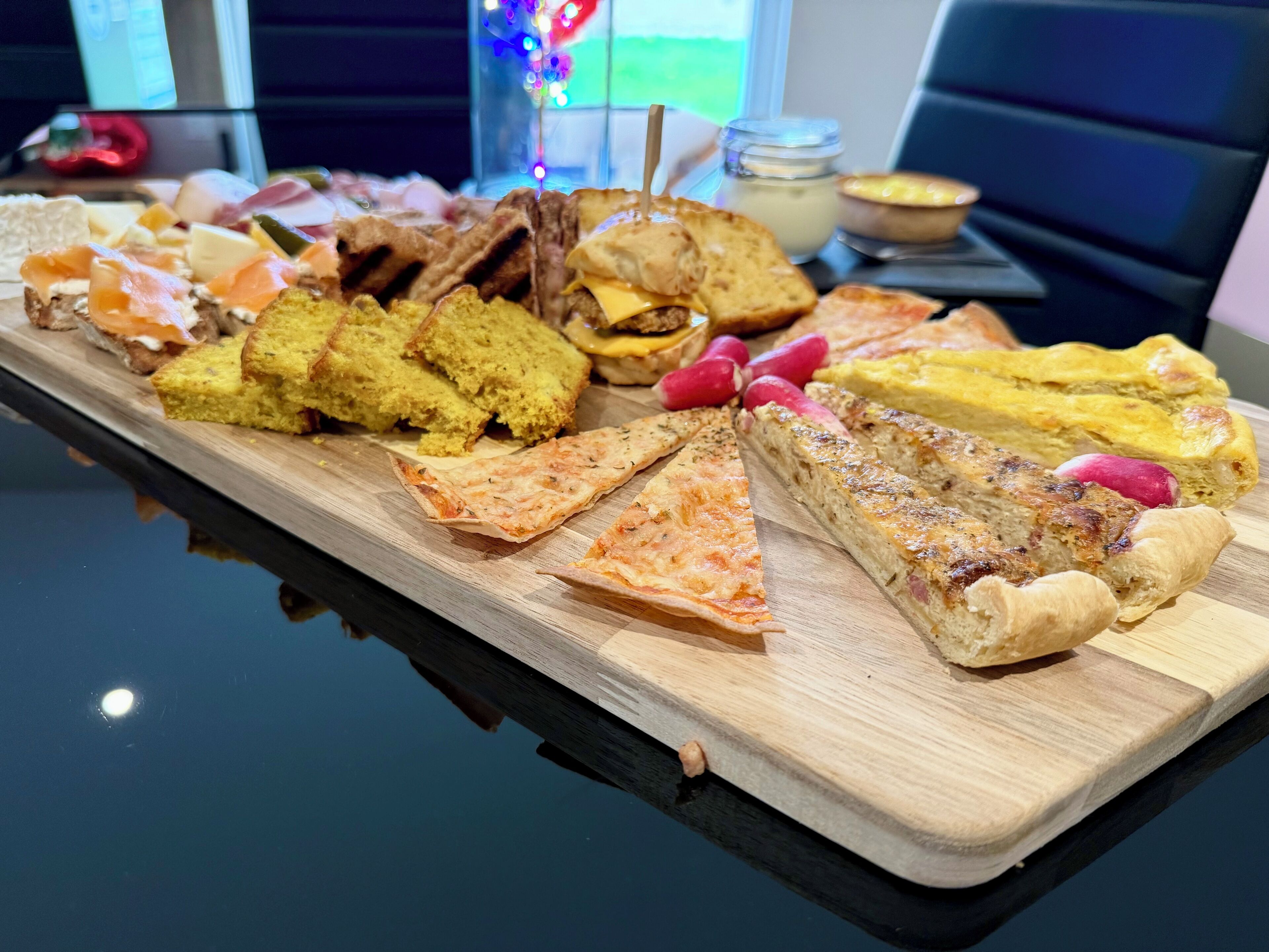 A wooden board with various food items including sandwiches, cheese, and bread.