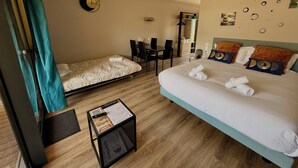 Hotellihuone, jossa on sänky, työpöytä, tuoli, pieni pöytä, jossa on ruokalista, ja seinäkello.