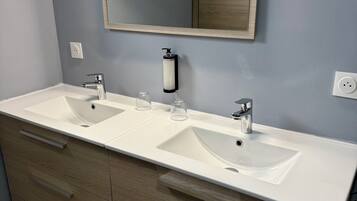 A modern bathroom with two sinks, a large mirror, and wooden cabinetry.