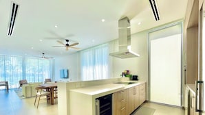 A modern kitchen with a central island, a dining area with a table and chairs, and a large window providing natural light.