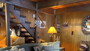 A cozy living room with a blue sofa, a wooden coffee table, and a staircase. - Rustic Sierra Cabin with Hiking Trail and Kids Room - Perfect Family Getaway! (Mi-Wuk Village)