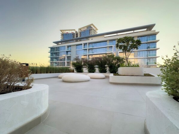 A modern building with multiple balconies and a spacious outdoor area with planters and seating.