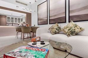 A modern living room with a sofa, a coffee table, and a dining area with chairs.
