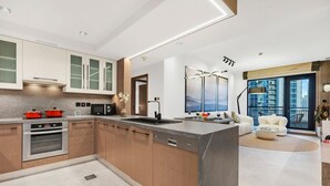 Une cuisine moderne dotée d’un îlot central, d’appareils électroménagers intégrés et donnant sur un balcon.