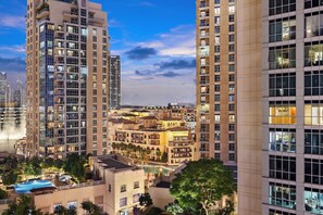 A high-rise hotel with multiple floors, a swimming pool, and a view of the city skyline.
