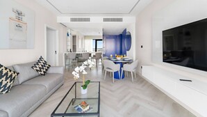 Un salon moderne avec un canapé, une table basse et un téléviseur. Il y a également un coin repas avec une table et des chaises.