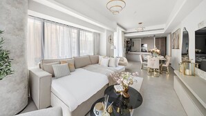 Ein modernes Wohnzimmer mit Sofa, Esstisch und einer Küche im Hintergrund.