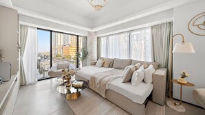 Ein modernes Schlafzimmer mit einem großen Bett, einer Couch, einem Couchtisch und Blick auf die Stadt.