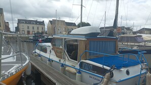 A marina with several boats docked, featuring wooden and metal structures, and a building with a sign in the background. - Vedette hollandaise 9m a quai a l'entrée de Redon  (Redon)