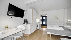 Une chambre d’hôtel moderne et minimaliste, dotée d’une kitchenette, d’un coin repas et d’un lit.