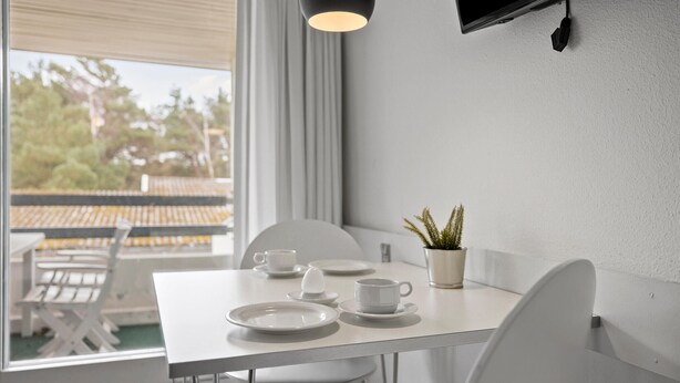 Un coin repas avec une table blanche, des chaises et une plante en pot.