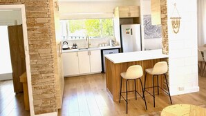 Eine moderne Küche mit einer Wand aus Stein, Holzschränken und einer Bar mit Hockern.
