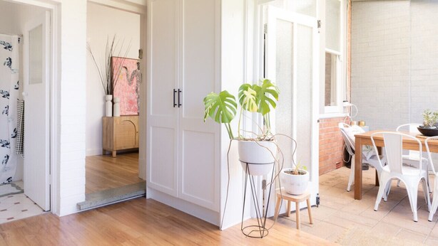Un espacio habitable amplio y luminoso con piso de madera, paredes blancas y un área de comedor con mesa y sillas.