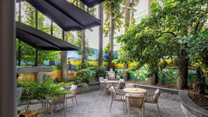 An indoor patio with wicker furniture, a tiled floor, and a mural of a landscape. - A25 Premium Hotel - 65G Nguyen Thai Hoc (Ho Chi Minh City)