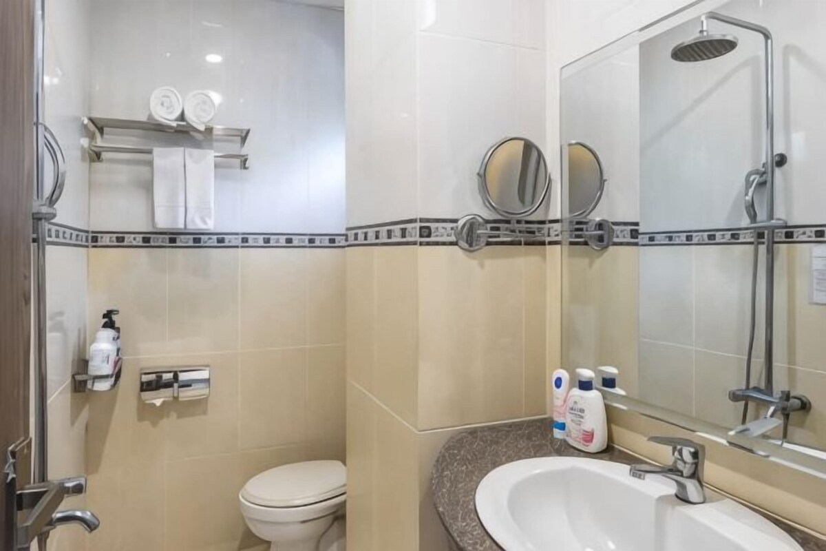 Un baño con inodoro, lavamanos y ducha. Hay toallas y artículos de aseo en la pared.