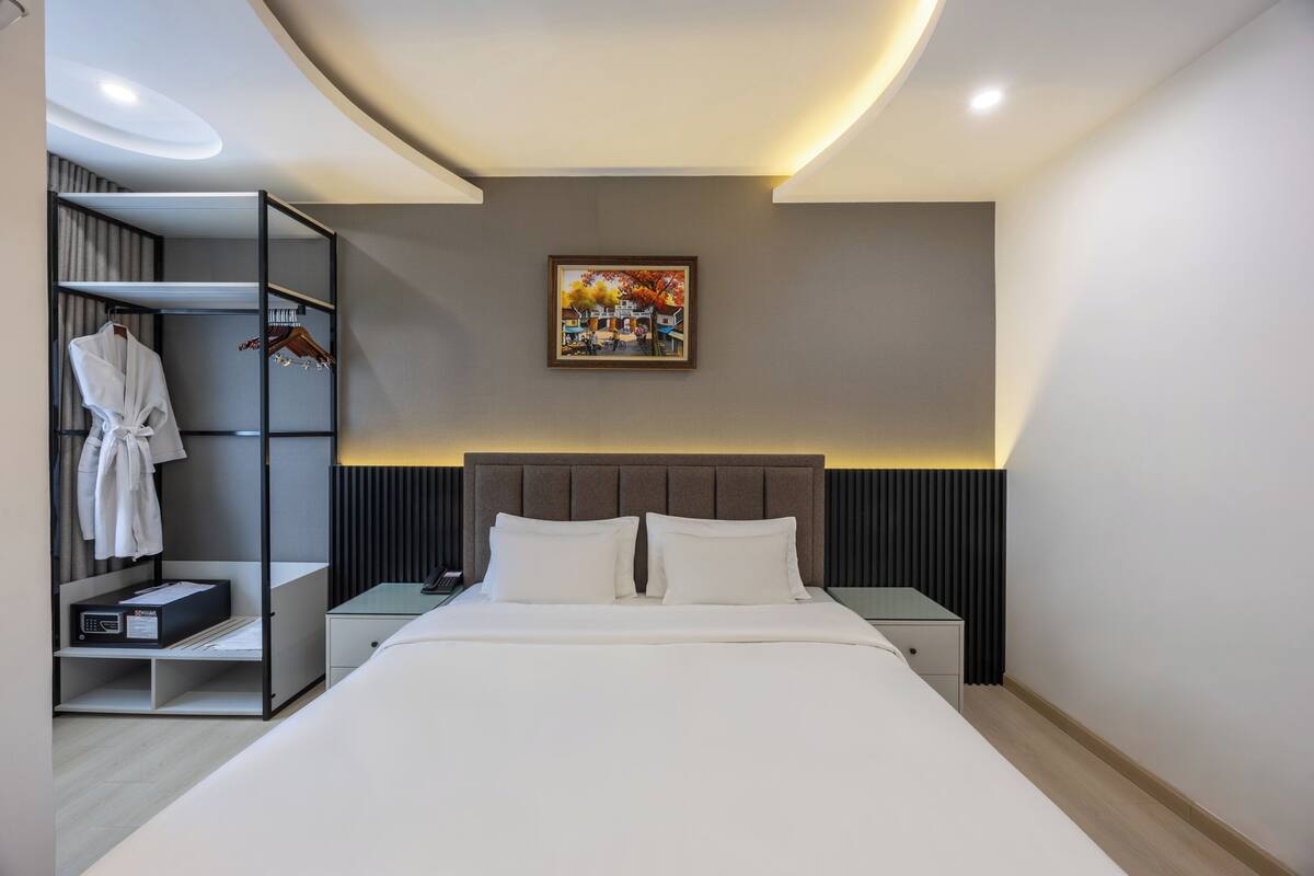 Ein modernes Hotelzimmer mit Bett, Nachttisch, Schrank und einem Bild an der Wand.