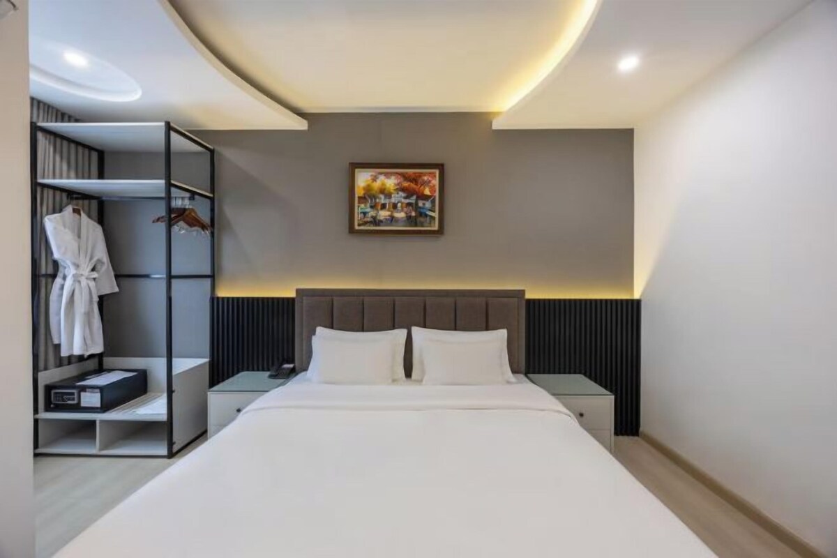 Una habitación de hotel moderna con una cama grande, una mesita de noche, un armario y un cuadro en la pared.