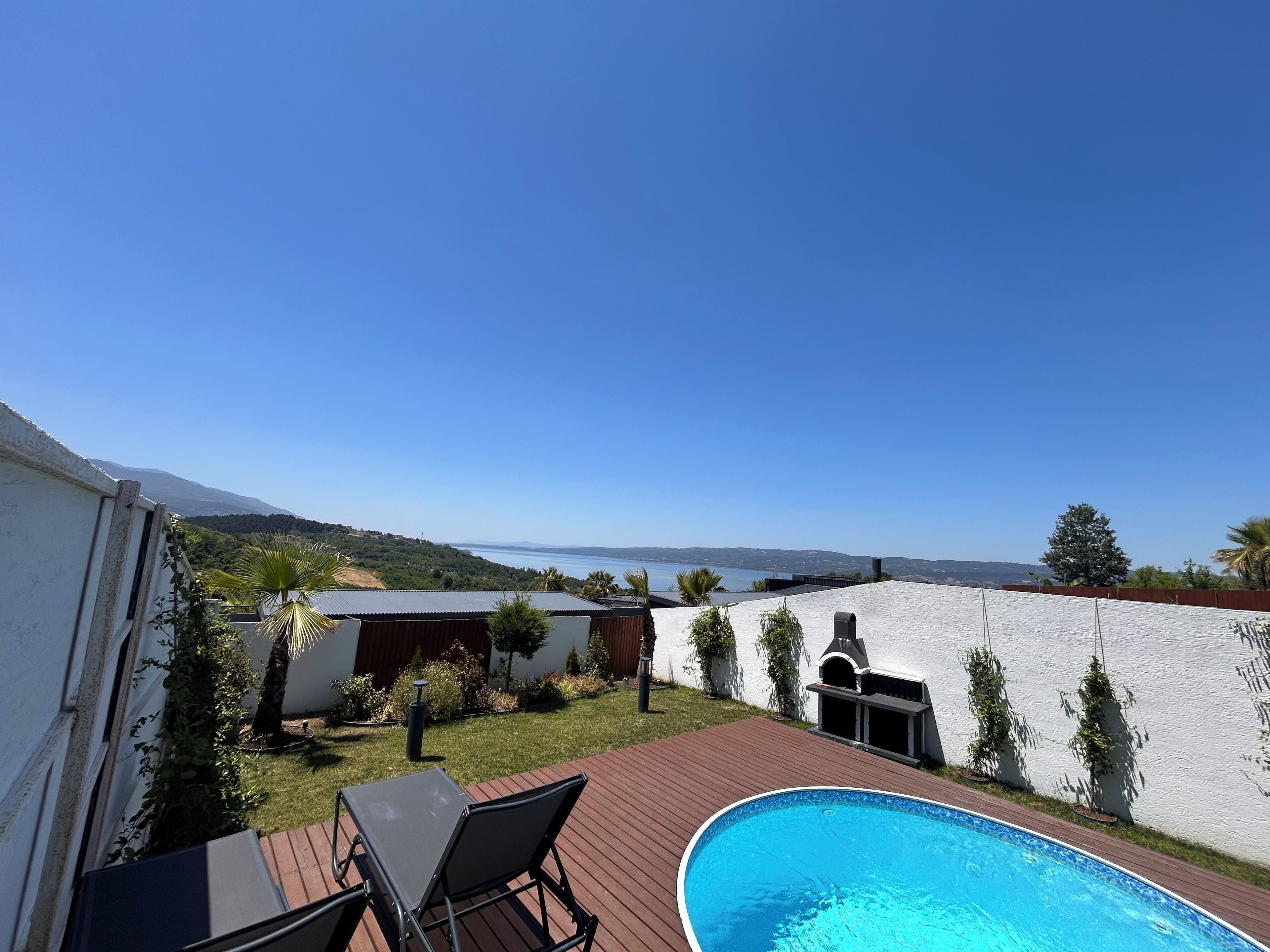 Un jardin avec une piscine, un espace barbecue et une vue sur la mer.