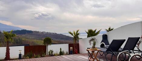 A circular pool with a wooden deck, two lounge chairs, and a table with fruits.