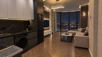 A modern kitchen with a built-in washer and dryer, a dining area with a view of the cityscape, and a living room with a large window.