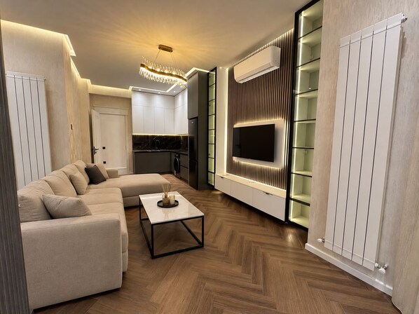 A modern living room with a sofa, a coffee table, and a TV mounted on a wall.