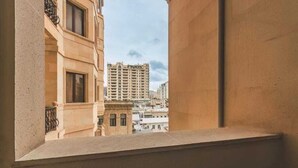 En utsikt från en balkong med en stenmur och ett fönster, med utsikt över en stadsbild med flera byggnader.