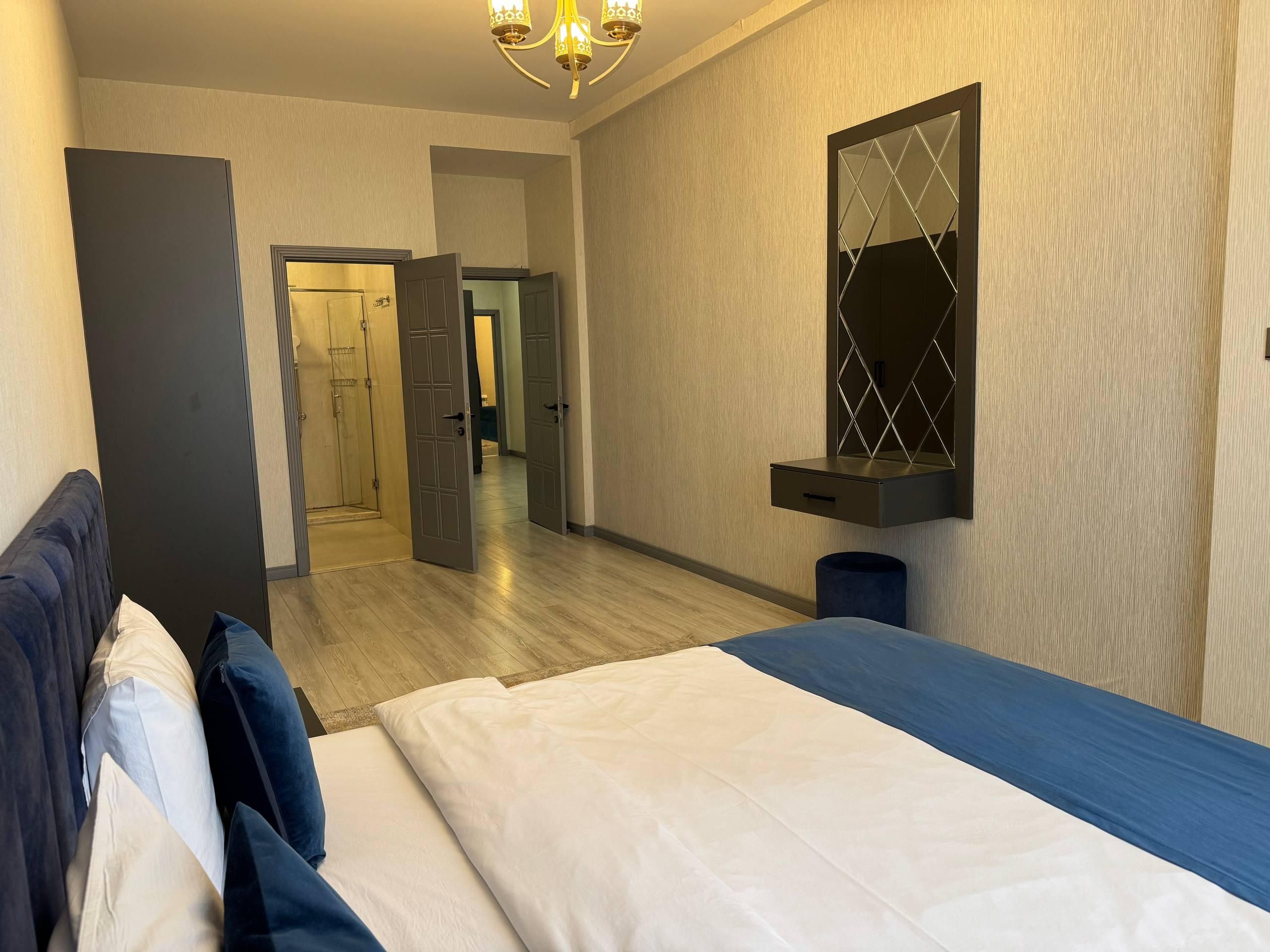 A hotel room with a bed, a bedside table, a mirror, and a wardrobe.