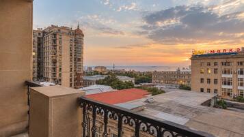 A balcony with a wrought iron railing overlooking a cityscape during sunset.