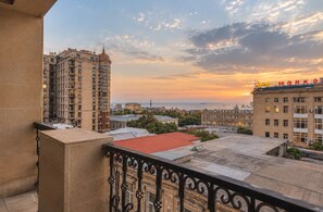 A balcony with a wrought iron railing overlooking a cityscape during sunset. - Apartments by Passage (Baku)