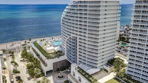 A high-rise hotel with multiple balconies, a pool, and a view of the ocean.