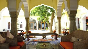 Un interior tradicional con muebles de mimbre, un banco central y vistas a un árbol fuera.