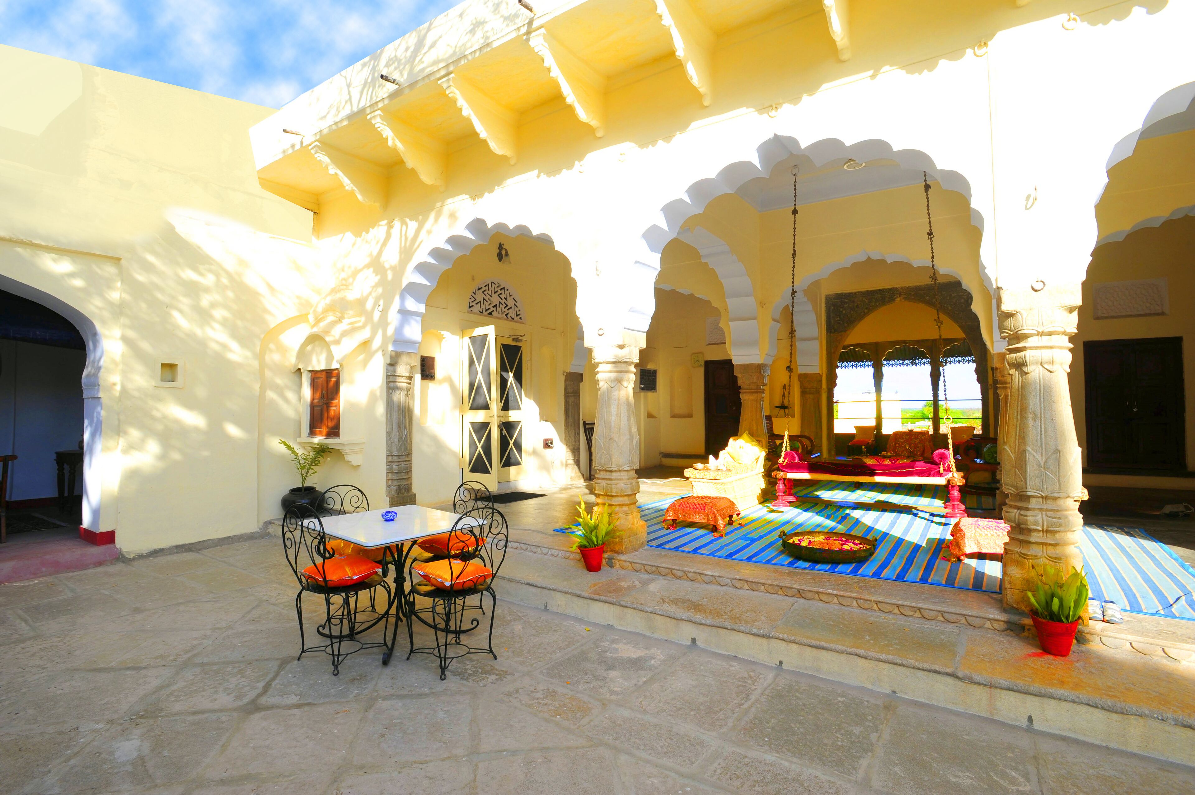 An outdoor seating area with a table and chairs, surrounded by arches and columns.