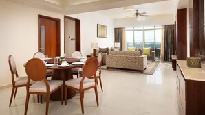 A spacious living area with a dining table, chairs, a sofa, and a large window offering a view. - Shangri-La Serviced Apartments, Yangon (Yangon)