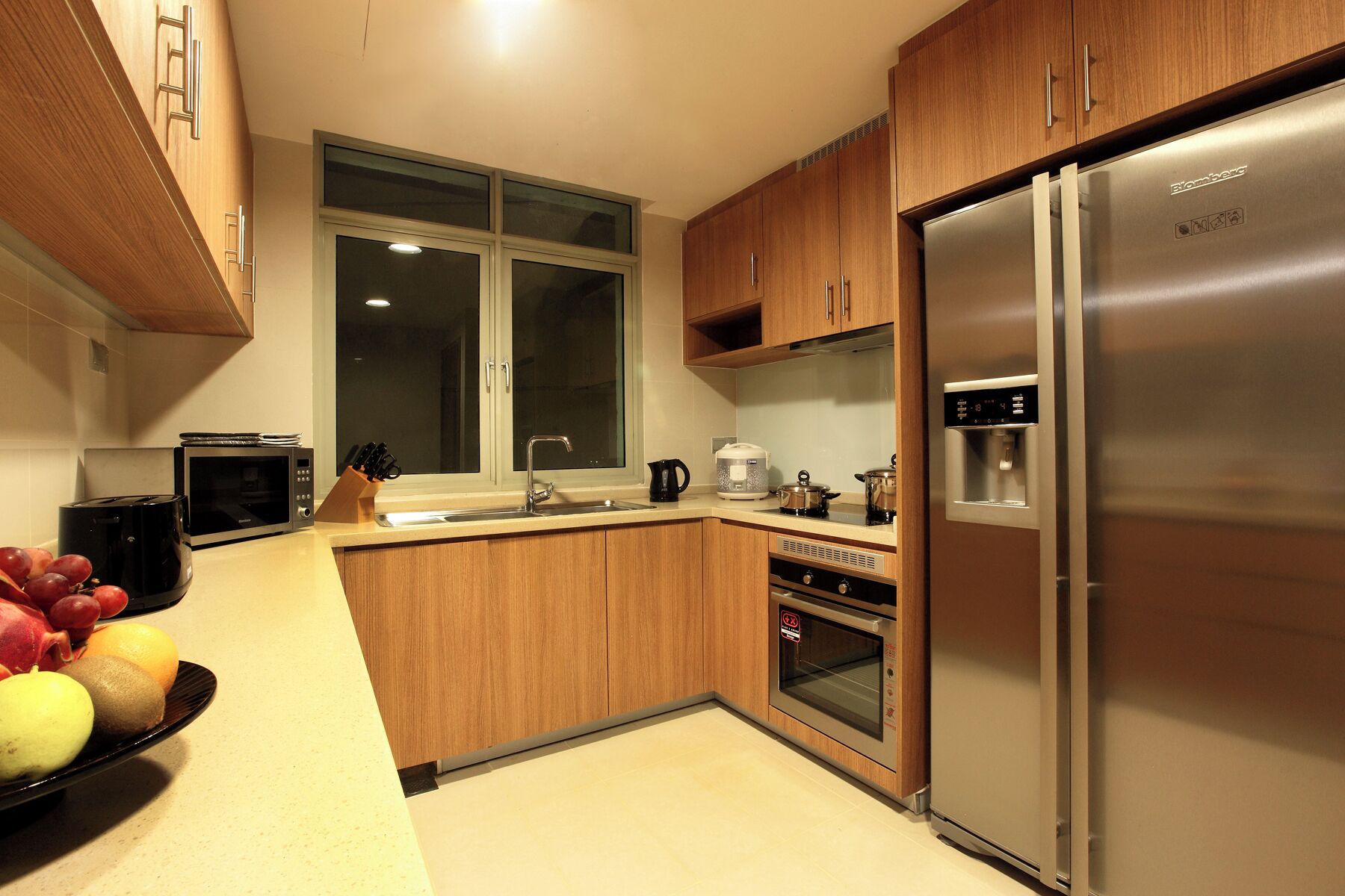Une cuisine moderne avec des meubles en bois, un réfrigérateur en acier inoxydable, un four à micro-ondes et un évier.