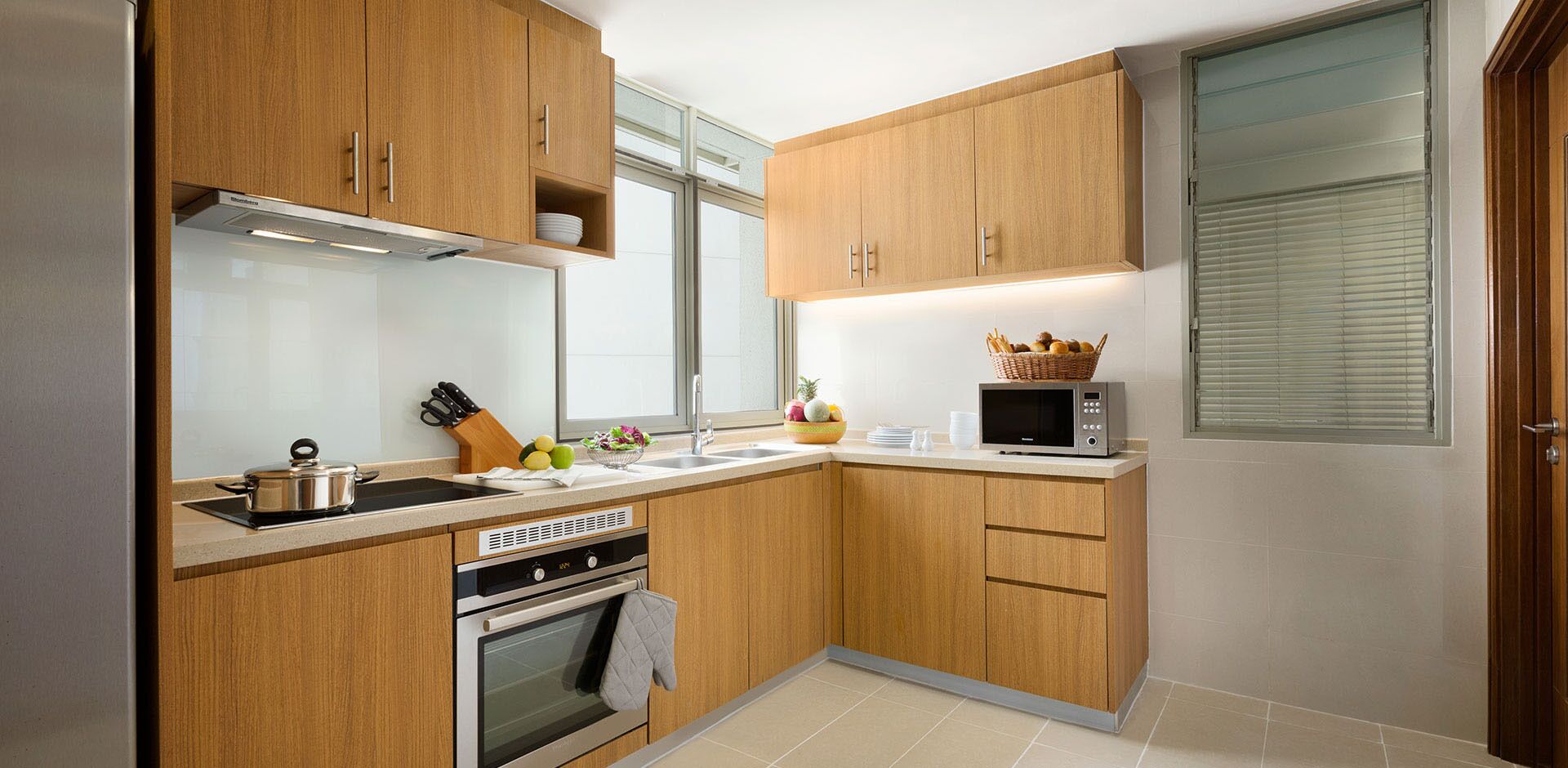 A compact kitchen with wooden cabinets, a microwave, a stove, and a sink.