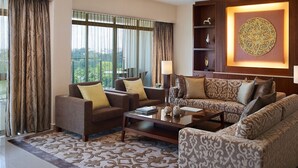 A modern living room with a sectional sofa, armchairs, and a coffee table. There are decorative items on shelves and a large wall art piece. - Shangri-La Serviced Apartments, Yangon (Yangon)