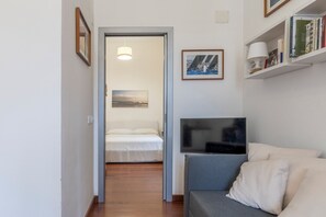 A modern hotel room with a bed, a TV, a sofa, and a bookshelf. - Casa con Accesso Privato al Mare Parcheggio Bogliasco (Bogliasco)