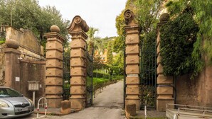A gated entrance with stone pillars and a metal gate, leading to a pathway flanked by greenery and buildings in the background. - Casa con Accesso Privato al Mare Parcheggio Bogliasco (Bogliasco)