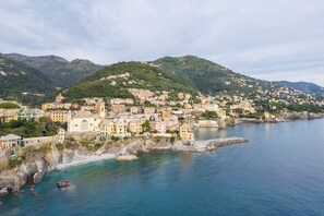 A coastal town with buildings along the shoreline, a prominent church, and a hill with scattered houses. - Casa con Accesso Privato al Mare Parcheggio Bogliasco (Bogliasco)
