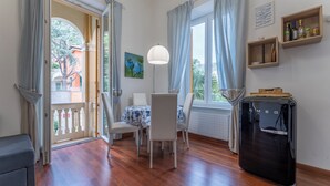 A dining area with a table, chairs, a lamp, a refrigerator, and a view of the outside. - Casa con Accesso Privato al Mare Parcheggio Bogliasco (Bogliasco)
