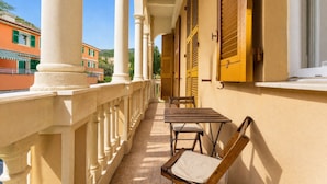 A balcony with a table and chairs, columns, and shutters. - Casa con Accesso Privato al Mare Parcheggio Bogliasco (Bogliasco)