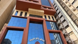 A modern hotel with a prominent glass facade and a red and beige color scheme. - Retaj Alhayat (Makkah)