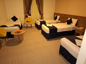 A hotel room with two beds, a small round table, a chair, and a telephone. - Retaj Alhayat (Makkah)