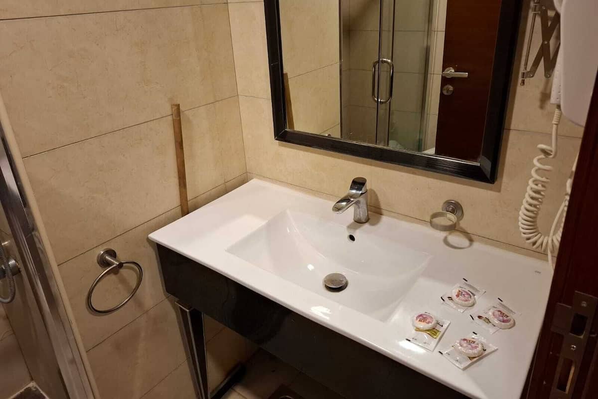 A bathroom with a white sink, a mirror, and a telephone.