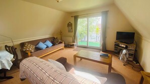 A living room with a sofa, a coffee table, a television, and a bookshelf. - River Lark Lodge (Isleham)