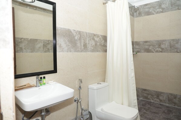 A bathroom with a white sink, mirror, and shower. - Nazri Hotel (Arambol)