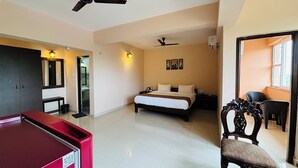 A hotel room with a bed, a desk, a chair, a wardrobe, and a ceiling fan. - Nazri Hotel (Arambol)