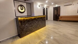 A reception area with a marble reception desk, a sofa, and a wall-mounted sign. - Nazri Hotel (Arambol)
